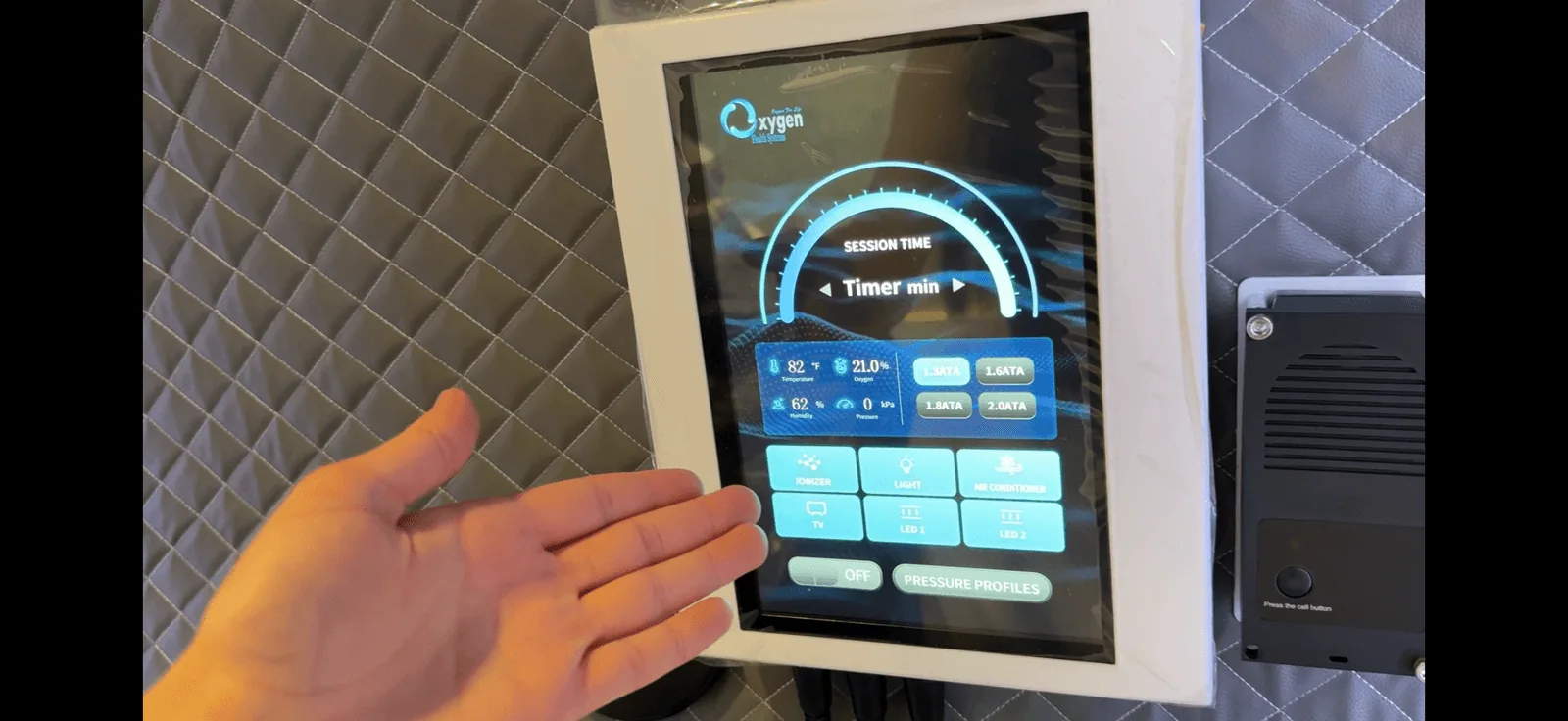 Intuitive high-definition internal touchscreen user interface mounted inside the chamber — showing session timer, real-time temperature, oxygen, humidity and pressure readouts, one-touch ATA pressure selection, and chamber controls